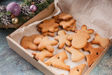 Traditional gingerbread cookies in a craft box and a Christmas wreath with decorations.