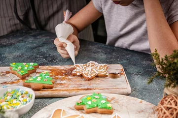 Foto op Canvas Girl decorate gingerbread cookies. Homemade traditional Christmas pastries. Delicious dessert. Hands of people close up. © yusev