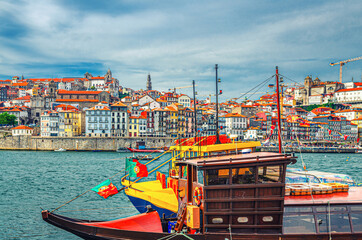 Traditional wine boats in water of Douro River and Ribeira district embankment with colorful buildings and typical houses in Porto Oporto city historical centre, Norte or Northern Portugal