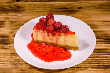 White plate with cheesecake New York and raspberries on wooden table