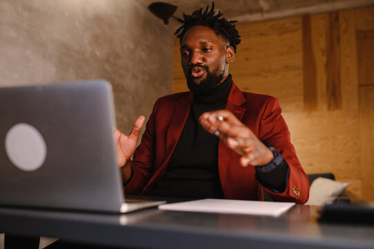 A Focused Black Man In A Suit Is Working On A Laptop. Remote Work From Home