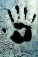 An imprint of a person's right hand on frozen glass. thawed patches on the glass.