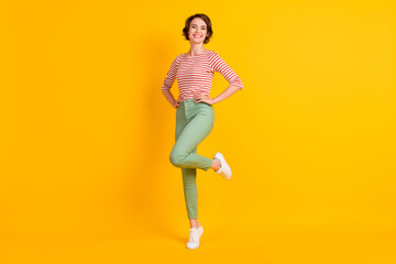 Fototapeta na wymiar Full length body size photo of cheerful girl smiling standing tiptoes isolated on vibrant yellow color background