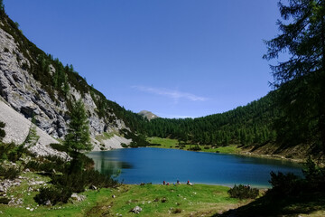 Fototapeta na wymiar hikers on a blue mountain lake with blue sky in the summer