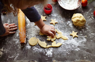 A cute little girl 3-4 years old sits on the windowsill and prepares Christmas cookies. Family...