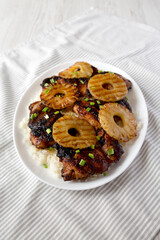 Homemade Hawaiian Huli Huli Chicken on a white plate on cloth, low angle view.