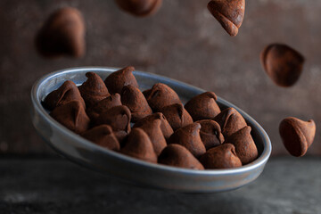 Truffle chocolate candy on ceramic plate. Flying food photo.