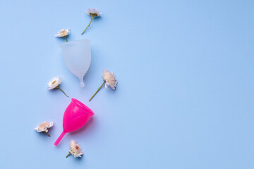 Obraz na płótnie Canvas Menstrual cup with flowers on blue background