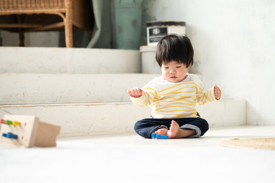 広い部屋で座っておもちゃで遊ぶ日本人の赤ちゃん　コピースペースあり 広角