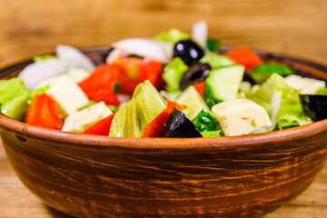 Ceramic plate with greek salad on wooden table