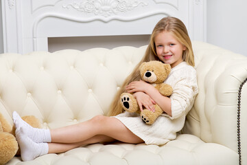 Girl sitting on sofa hugging teddy bear