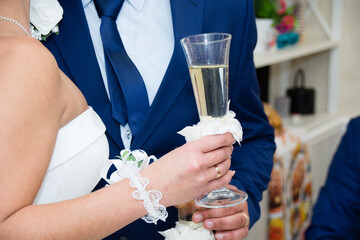 Champagne glass of wine in hand of the bride in a white dress