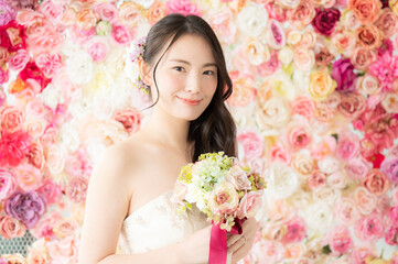 Obraz na płótnie Canvas 背景がバラの花でブライダルにも使えるかわいい花嫁さん3　正面向きコピースペースあり