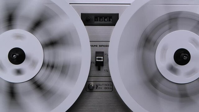 Old reel to reel tape recorder rewinds retro tape. Vintage music player close up. Spinning reels metallic color.