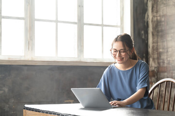 パソコンと本を開いて調べながら仕事をする美しい眼鏡の似合う日本人女性9 バストアップ　コピースペースあり