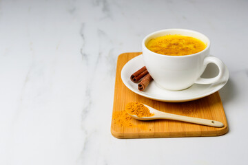 Turmeric golden spicy latte in white cup on marble table