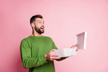 Portrait of attractive cheerful amazed guy opening giftbox having fun miracle copy space isolated over pink pastel color background