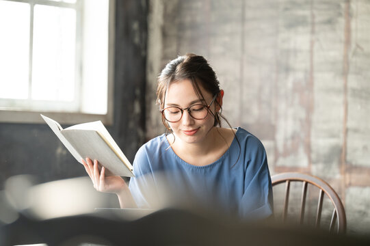 パソコンと本を開いて調べながら仕事をする美しい眼鏡の似合う日本人女性2　バストアップ