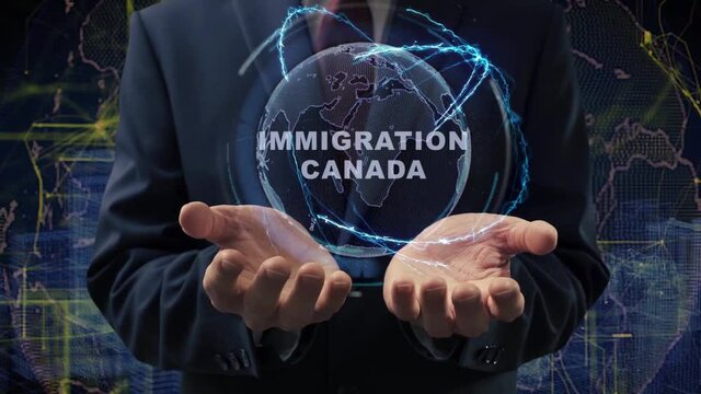 Male hands activate a conceptual holographic text Immigration Canada. Businessman in a suit with a hologram of planet Earth on a background of a futuristic wireframe city
