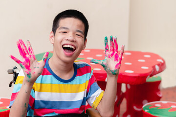 Asian disabled child on wheelchair smiling with his hands were stained with watercolor, Skills to...