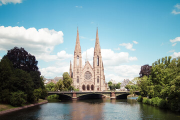 Fototapeta na wymiar Scenic view of St. Paul's Church and a bridge that leads over the Ill river in the city of Strasbourg, France under a clear blue sky.