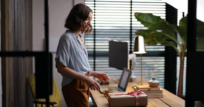 Young woman surprised seeing the gift box on the workplace in office. Concept of pleasant surprises at work