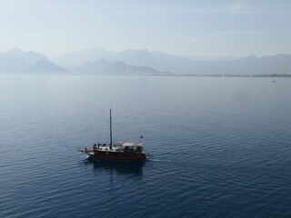 Antalya, Turkey, October 25, 2020: A single-masted gulet motoring in the still waters of the Mediterranean, hills of the Turkish Riviera in the background.