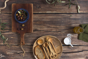 a plate of olives, several working tools, a small pitcher with olive oil on an aged wooden table. Top View. Food Concept