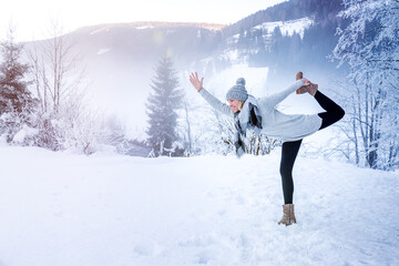 Woman practicing yoga in a landscape with snow in winter