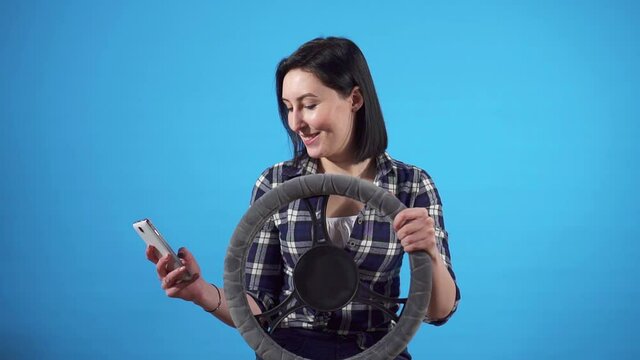 portrait istracted female driver uses smartphone at the wheel and gets distracted from driving