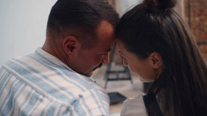 Happy couple together sitting on floor and cuddling in renovated apartment