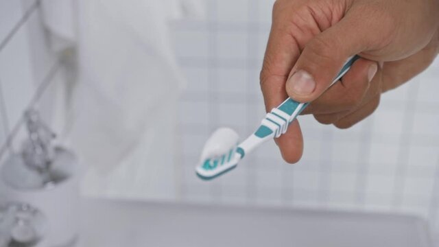 focus pull of man squeezing toothpaste on toothbrush