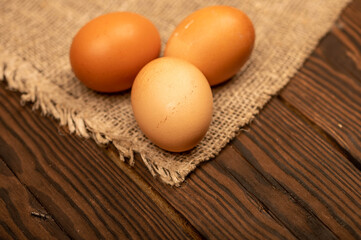 A few yellow, large chicken eggs on a background of homespun fabric with a rough texture. Close-up, selective focus.