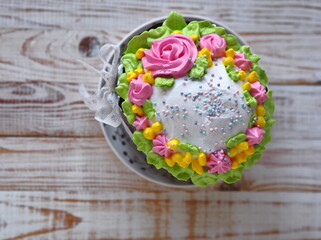 Homemade Easter cake, anointed with cream and roses and decorated with a bow of pink ribbon. The...
