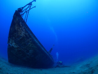 scuba divers exploring shipwreck scenery underwater ship wreck deep blue water ocean scenery of...