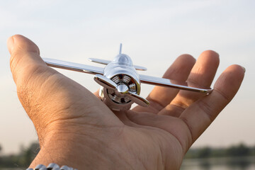 Travel concept. Male hands holding figurine of passenger plane. The plane is flying to the globe.