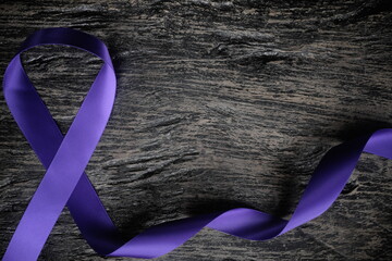 Top view of  violet ribbon on dark wood background with copy space. Hodgkin lymphoma cancer...