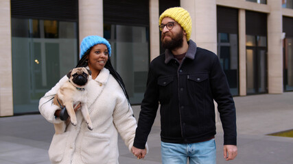 Young diverse couple have walk together with dog outdoors