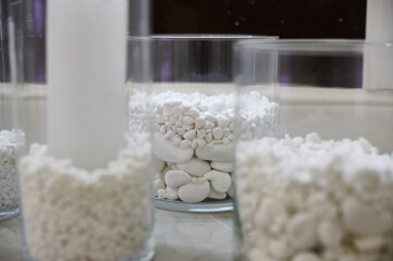 Close up of stones and candle in a transparent glass vase on marble table in a beauty salon