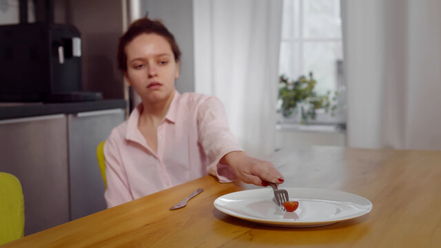 Anorexic woman feels dizzy depleted by severe diet trying to eat tomato