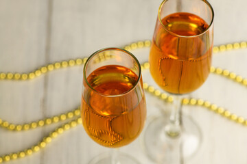 .Two glasses of champagne, wine on a light background with gold beads. Alcoholic drink: champagne, beer, white wine. New year and Christmas background. Valentine's Day