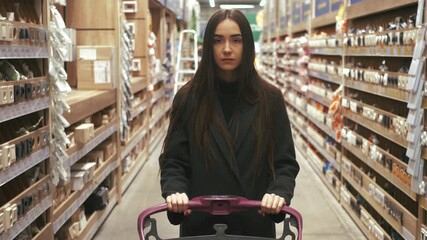 Woman choosing some stuff in hardware store. Pushing shopping cart buying materials in house improvement store