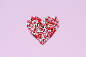 Heart shape made of a small heart shaped candy on pink background. Valentines day candy hearts.