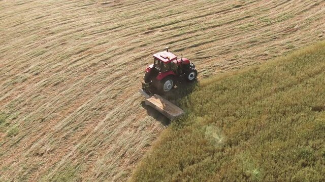 A tractor cutting down Barley with a farm tractor machine. Dried to make Hay