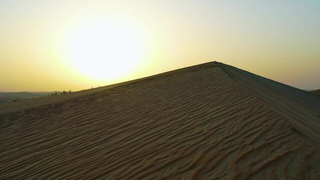 Aerial view over a sand dune, in middle of desert, revealing the sunset, - rising, drone shot