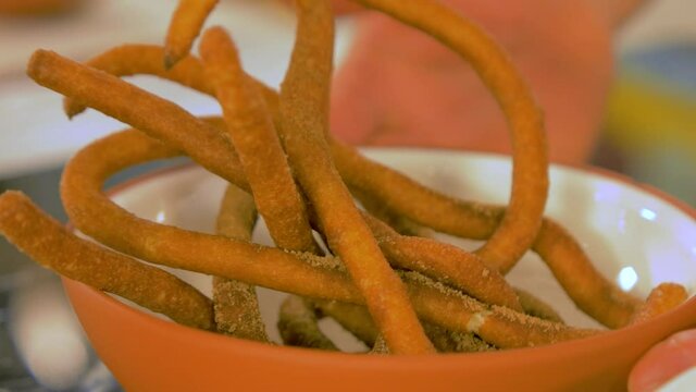 Rotating white clay bowl with tasty garnetted dough biscuits sprinkled with cinnamon, handheld close up shot
