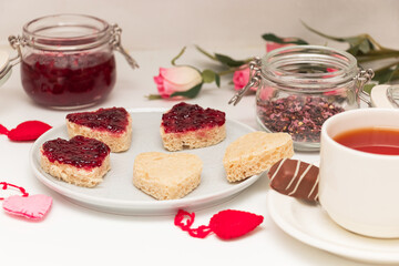 Romantic breakfast for valentine's day. bread in the form of hearts with jam and flower tea.