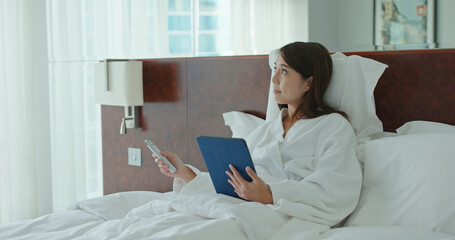 Woman use of tablet computer and control the curtain by remote at hotel room