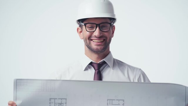 architect in hardhat covering face with blueprint and smiling isolated on white