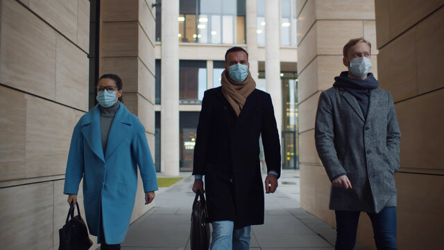 Business people in medical masks walking to office outdoors